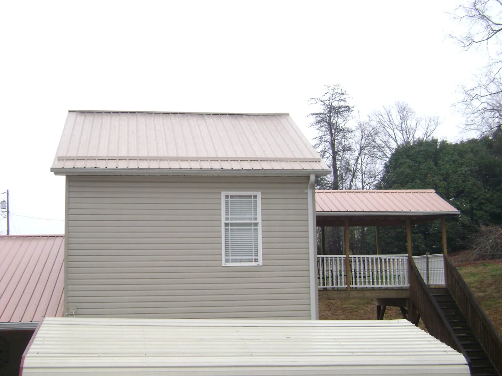 Tan metal roofs on a two story addition and attached porch, from a Roof Replacement job in Oxon Hill
