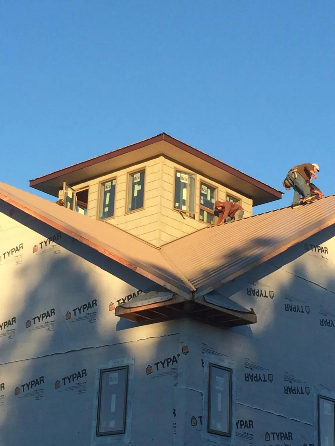 Roofers working around a rooftop cupola on a new metal roof at sunset — Roof Waterproofing in Oxon Hill by Roofing Brothers